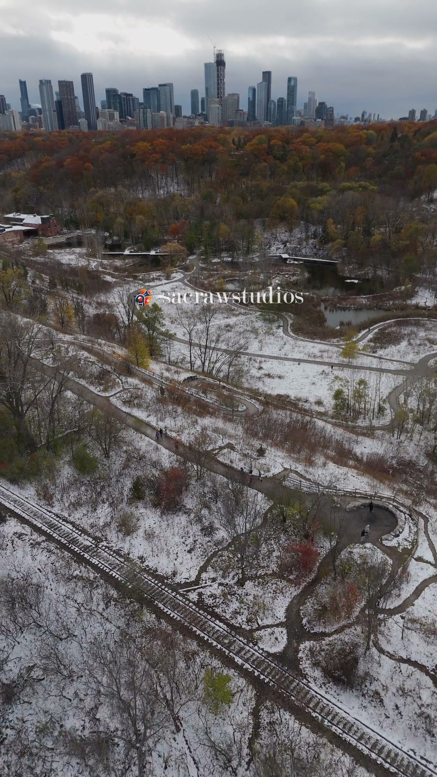 Snowy Park and Rail Tracks with City Skyline - Aerial