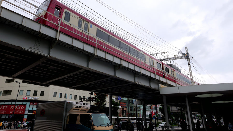 Red Train Crossing Elevated Railway Above Busy Japanese Street Intersection