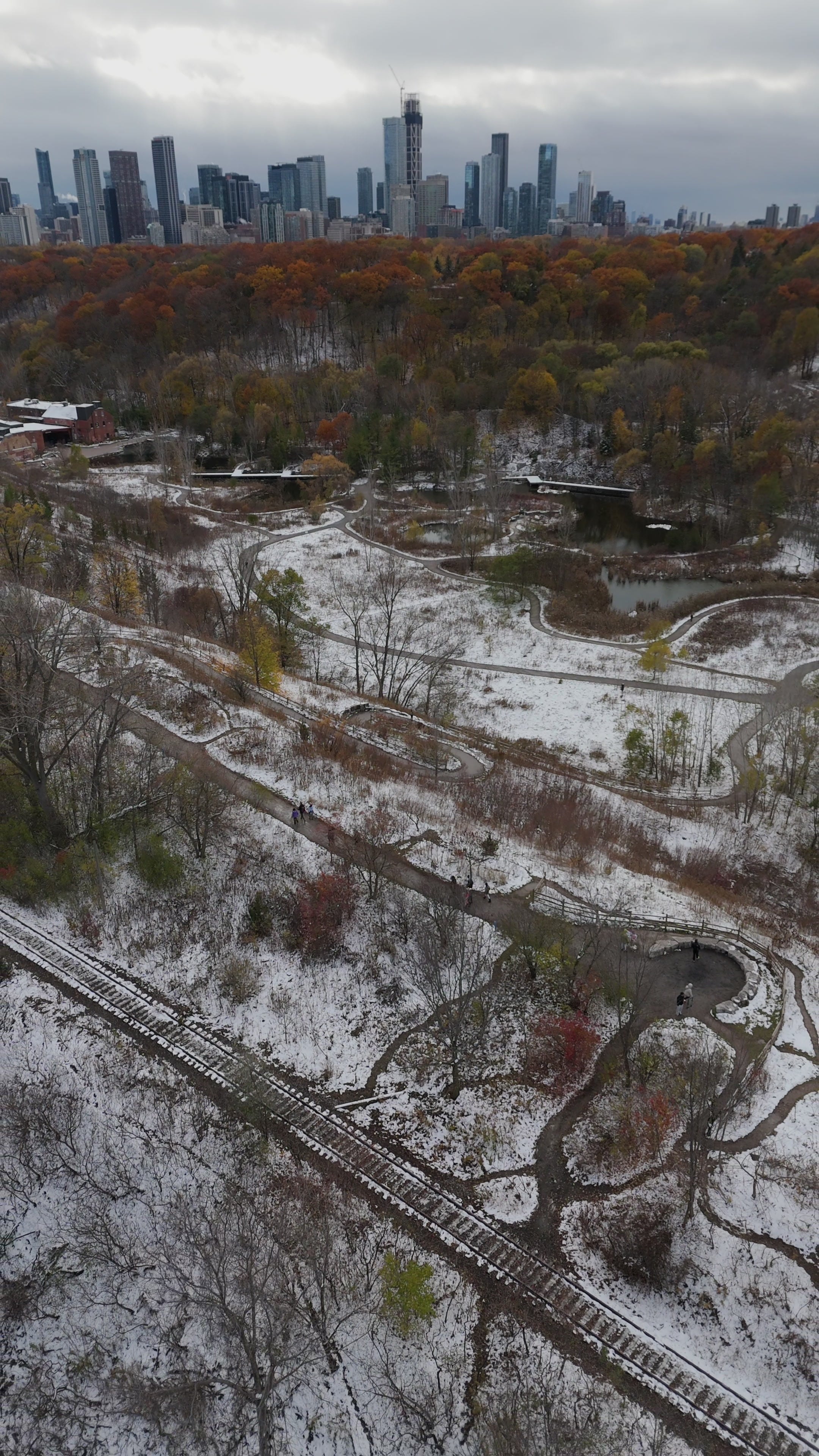 Snowy Park and Rail Tracks with City Skyline - Aerial in winter — 4K stock footage