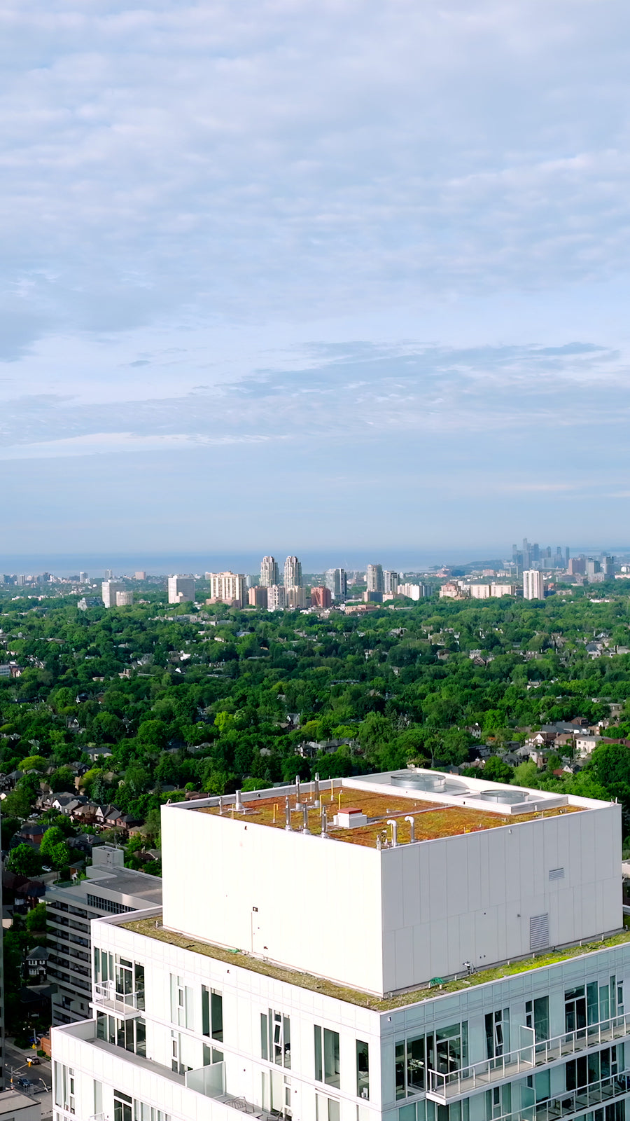 White Condo with Green Roof and Skyline - 4K Aerial