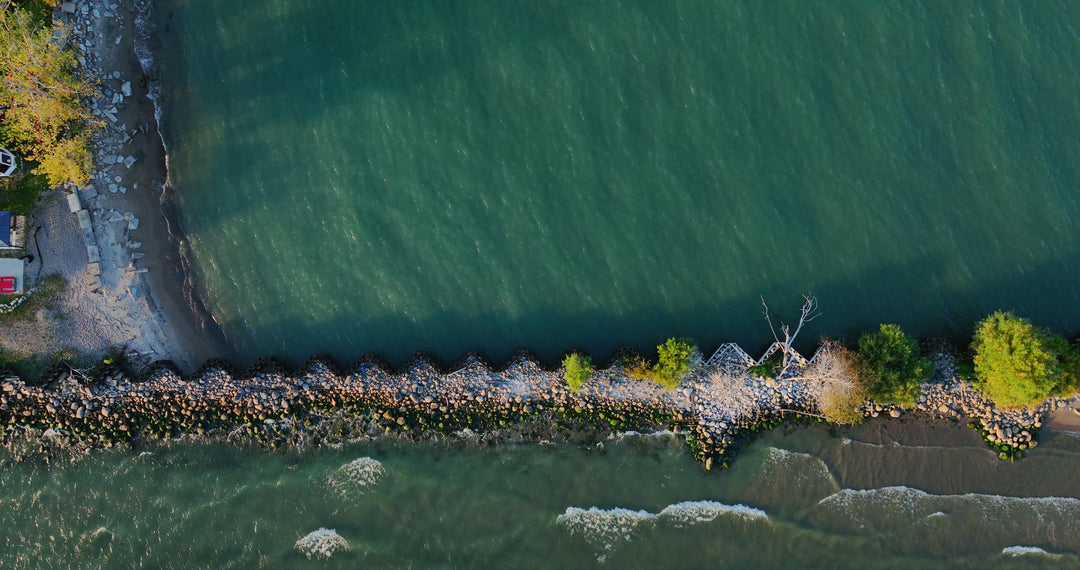 Aerial View of Rocky Breakwater with Turquoise and Dark Water Convergence — Premium 4K stock footage