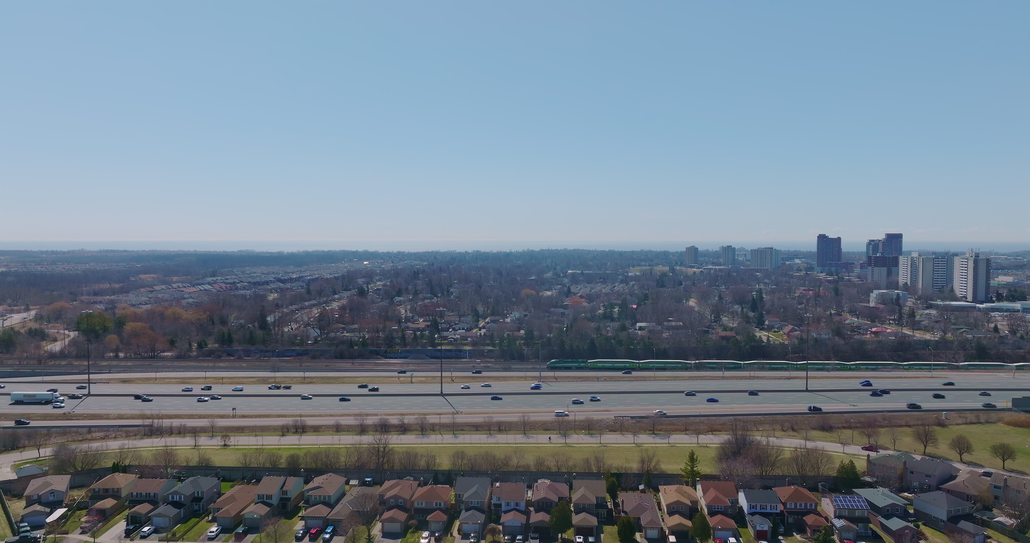 Highway Traffic with Commuter Train and Skyline - Aerial — 4K stock footage