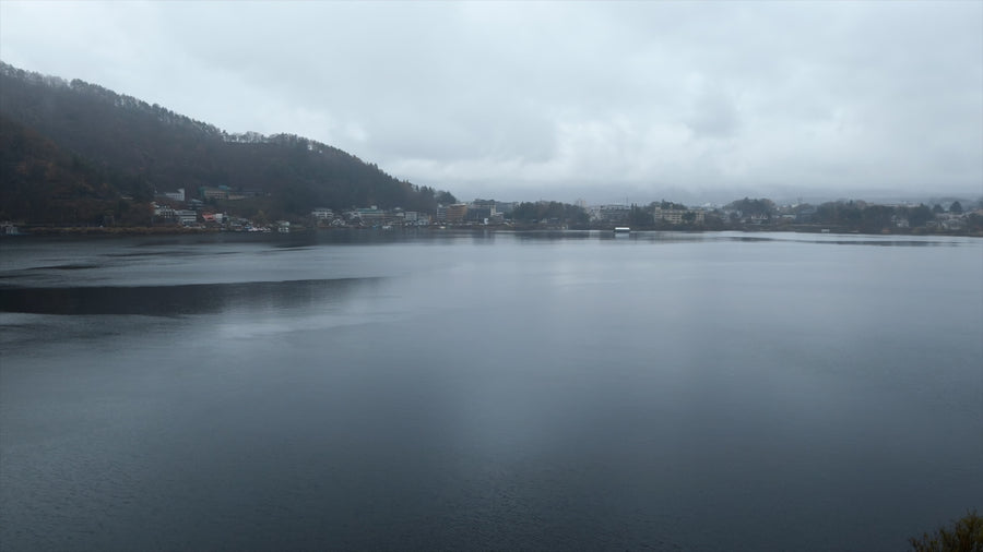 Misty Mountain Lake with Lakeside Town Under Overcast Sky