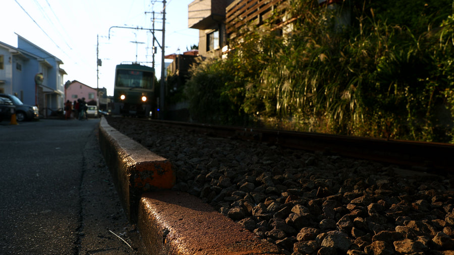 Japanese Local Train Passing Through Residential Neighborhood at Sunset