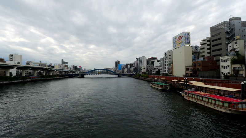 Tokyo Sumida River with Traditional Boats and Urban Skyline Under Cloudy Sky