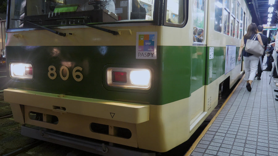 Commuters Boarding Green and Cream Tram at Night Station