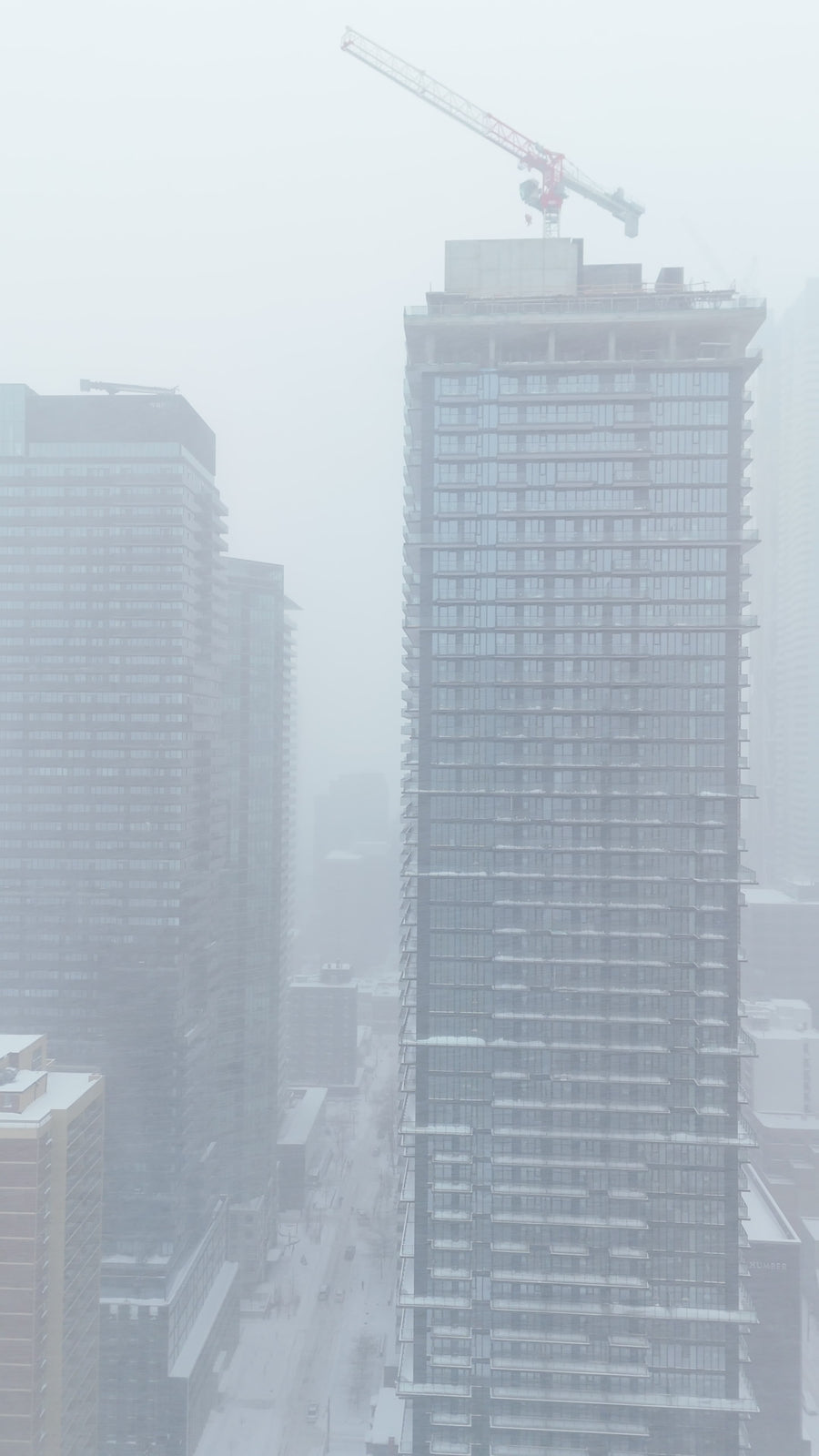 Skyscraper Construction Crane in Snowy Winter Fog
