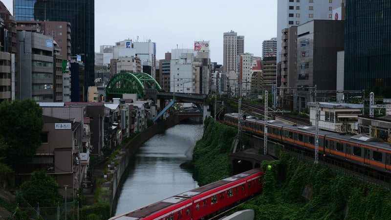 Tokyo Trains Passing Over Canal at Dusk with City Skyline