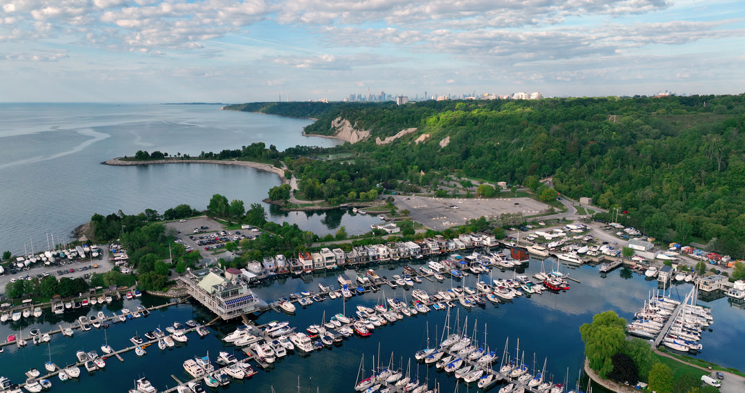 Aerial View of Coastal Marina with City Skyline and Forested Cliffs — Premium 4K stock footage