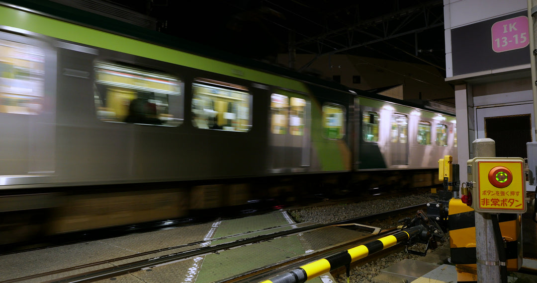 Japanese Commuter Train Passing Railroad Crossing at Night in Tokyo