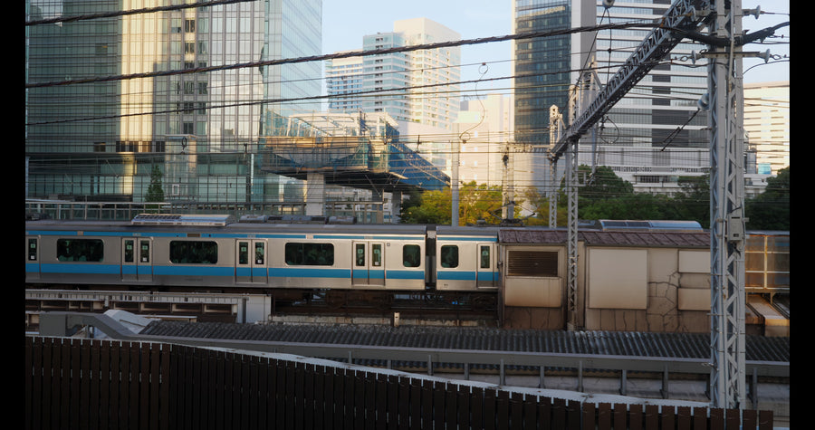 Tokyo JR Train Passing Through Modern Cityscape at Golden Hour