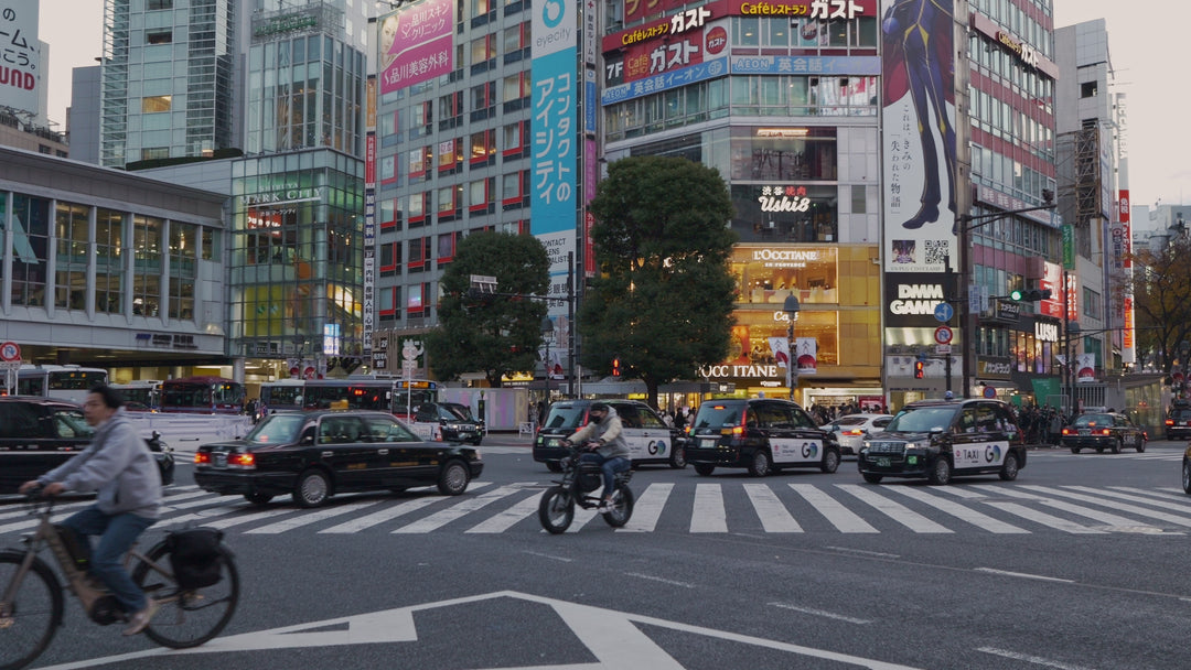 Busy Tokyo Street Intersection with Cyclists and Traffic at Dusk