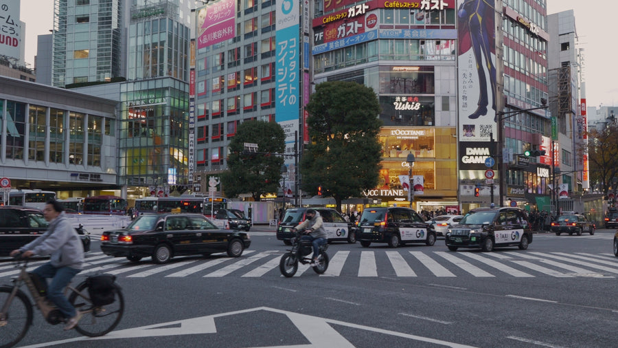 Busy Tokyo Street Intersection with Cyclists and Traffic at Dusk