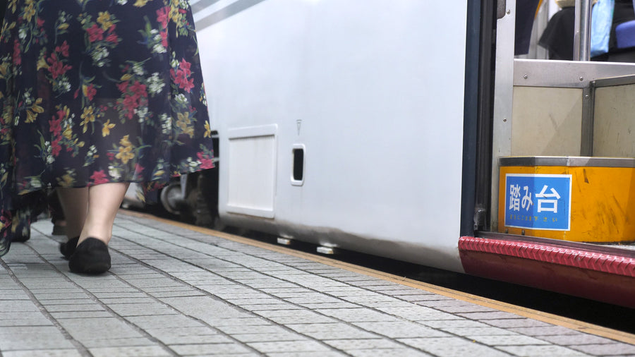 Woman in Floral Dress Walking Past Japanese Bus Stop Platform