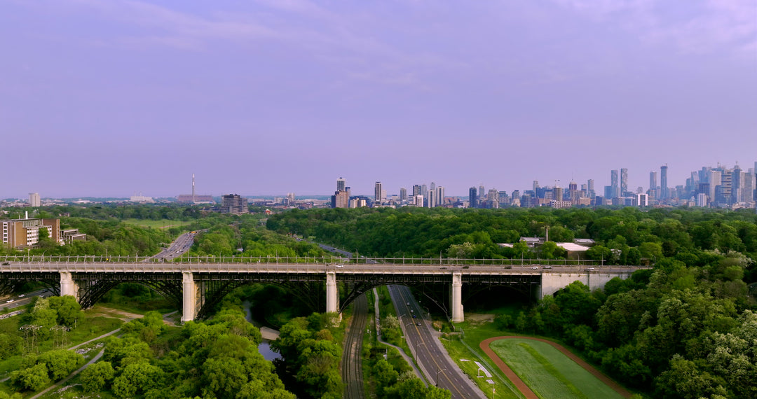 Aerial View of Bridge with City Skyline and Green Valley at Dusk — Premium 4K stock footage