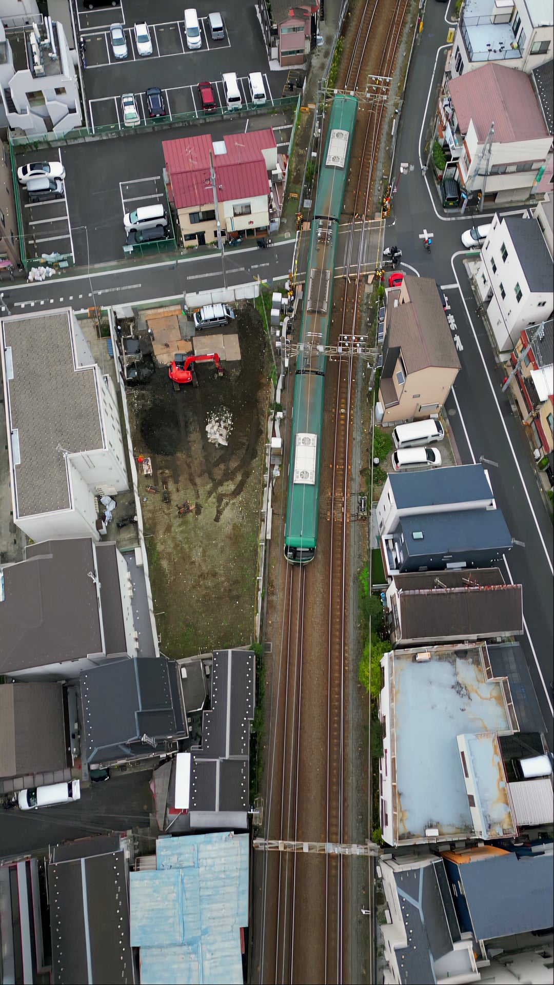 Aerial View of Green Train Passing Through Japanese Residential Neighborhood — Premium 4K stock footage