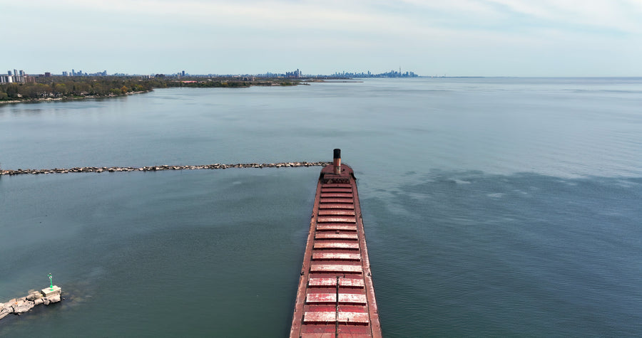 Sunken Shipwreck in Calm Harbor with Distant City Skyline - 6K Aerial