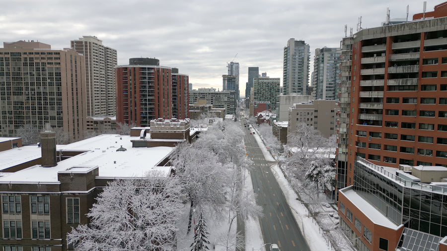 Snow-Covered City Street with Modern Skyline - 5K Aerial