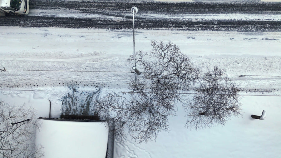 Snowy Urban Street with Truck and Pedestrians - Winter Aerial