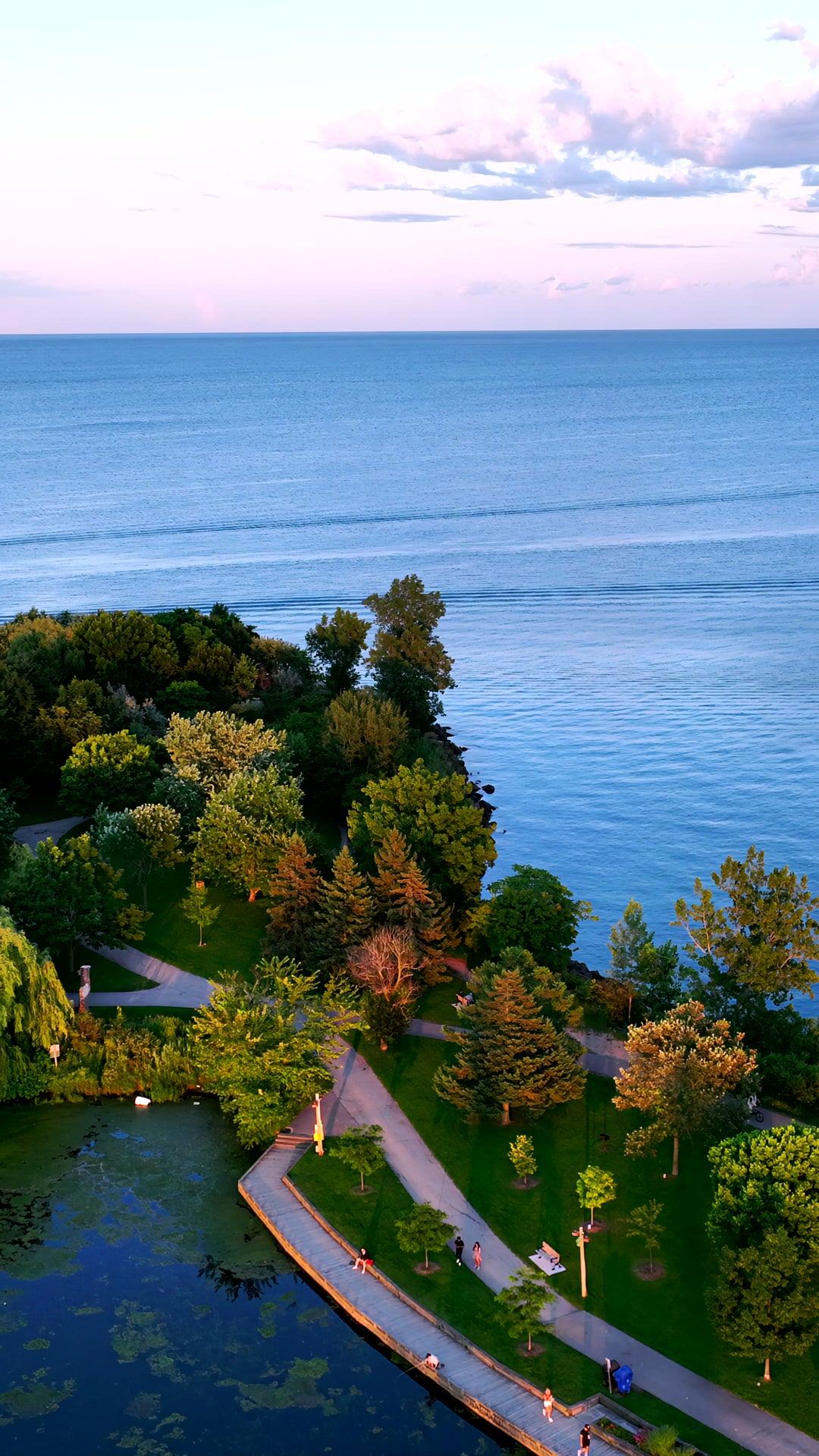 Aerial View of Coastal Park at Sunset with People Walking on Path — Premium 4K stock footage