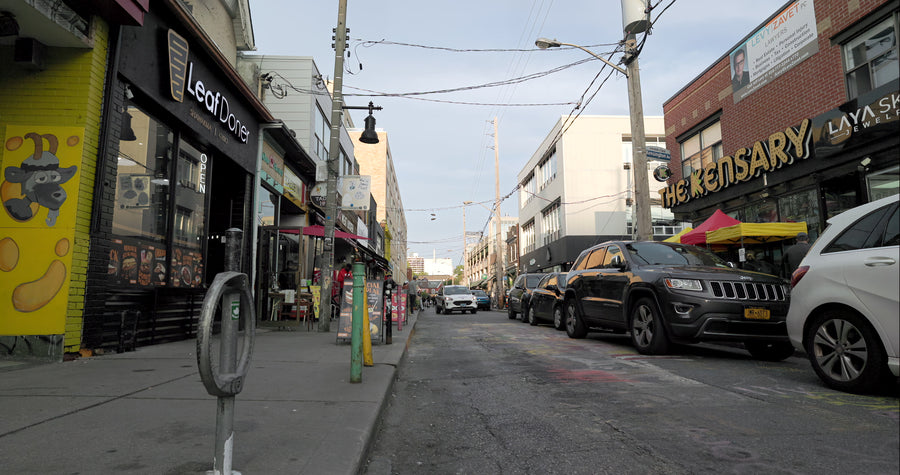Urban Street Scene with Shops and Pedestrians Walking on Sidewalk